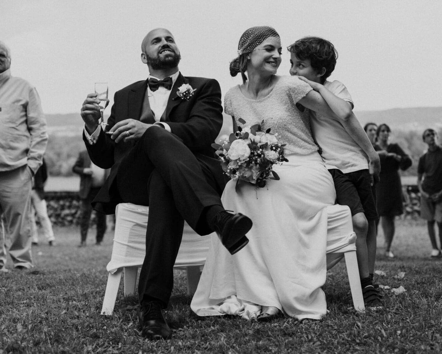 Les mariés écoutent un discours, clopes à la main – moment naturel et authentique pendant leur mariage en Isère