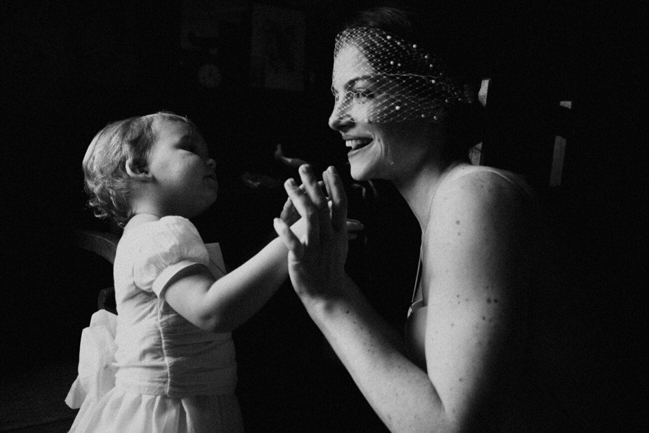 Photographie en noir et blanc d’une mariée partageant un moment complice avec un enfant pendant un mariage à Beaurepaire, Isère