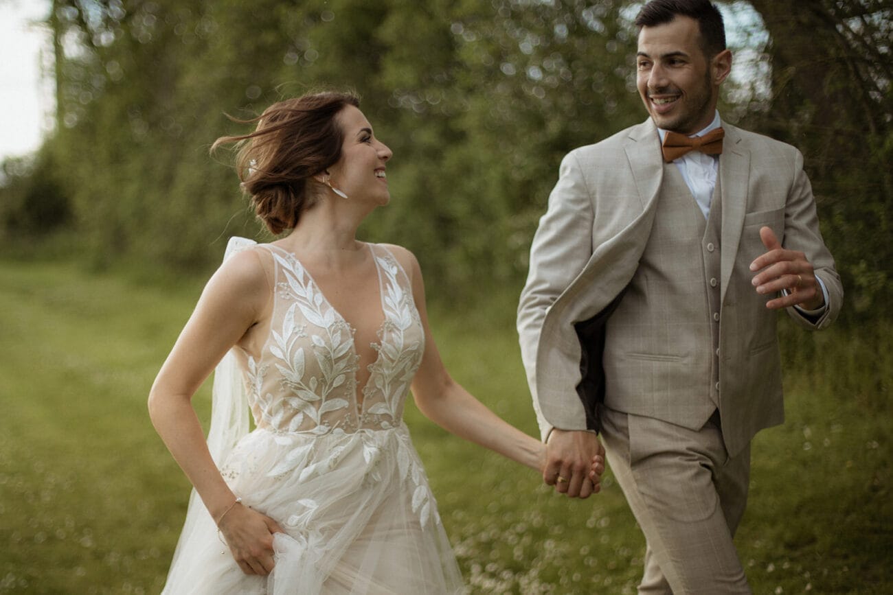 Un couple de mariés qui court main dans la main, loin des invités.