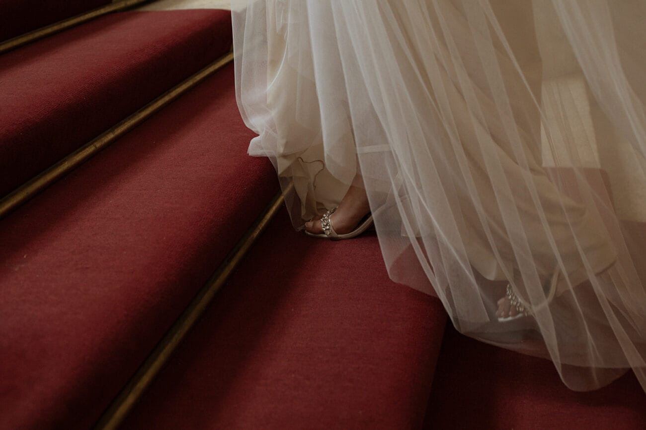 Photographie artistique d’une mariée descendant un escalier rouge à Lyon, capturée par un photographe de mariage