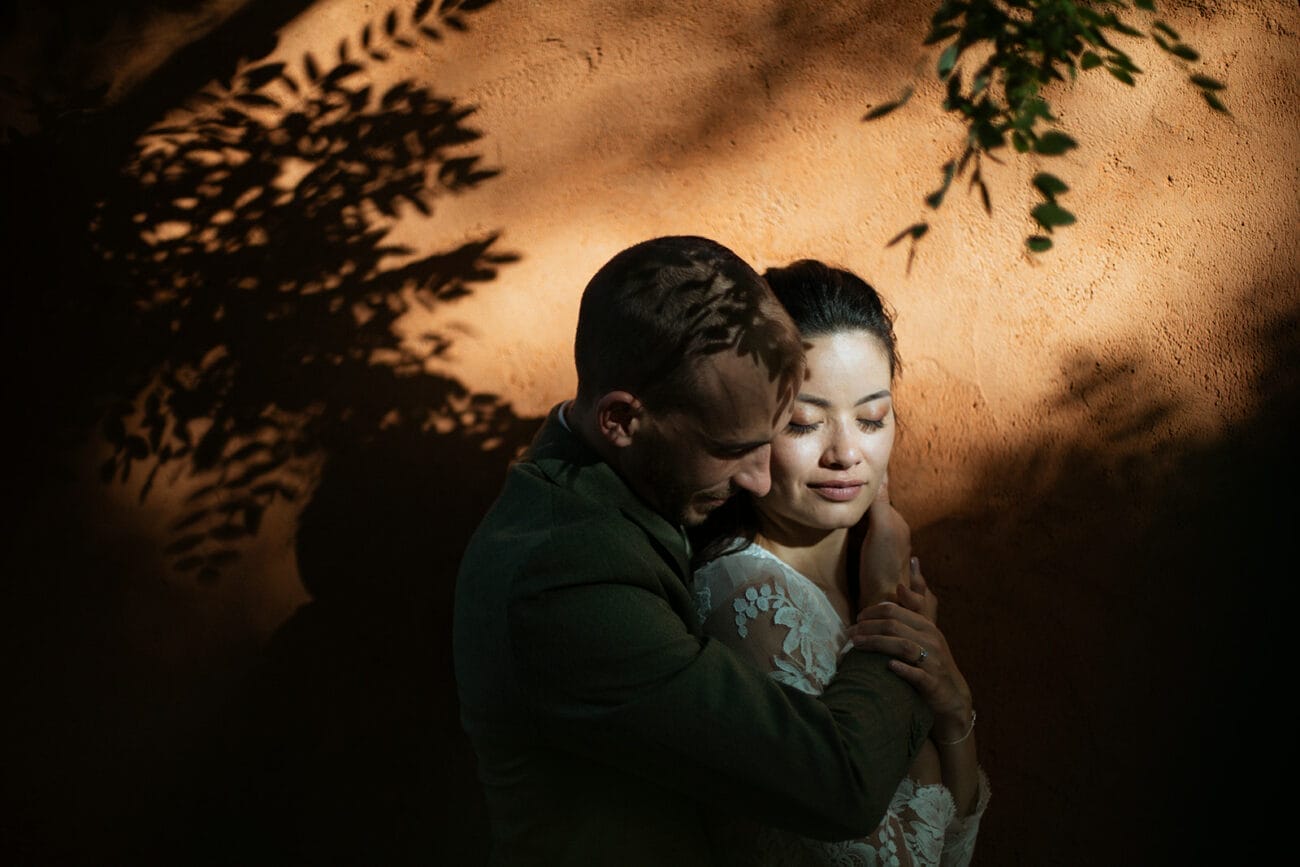 Photographe mariage à Bangkok – Couple enlacé dans une lumière dorée projetant des ombres végétales
