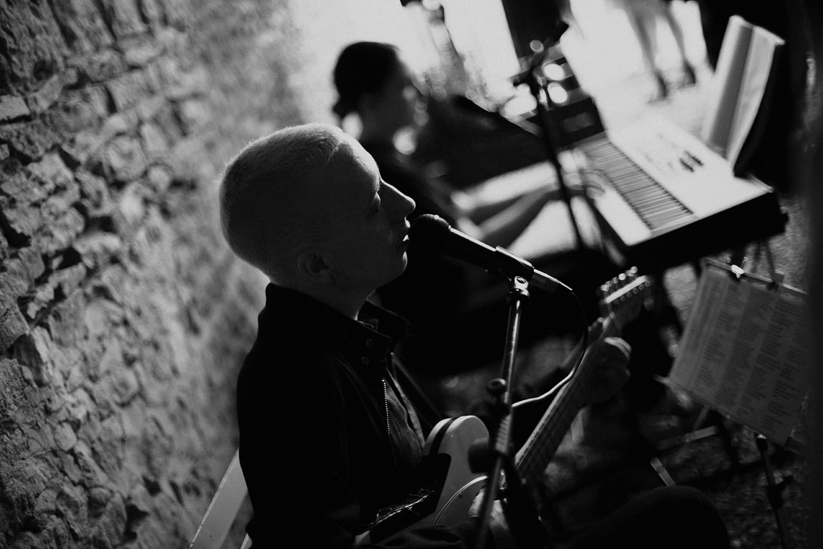 Musicien live en noir et blanc pendant un cocktail de mariage, ambiance intimiste et authentique.