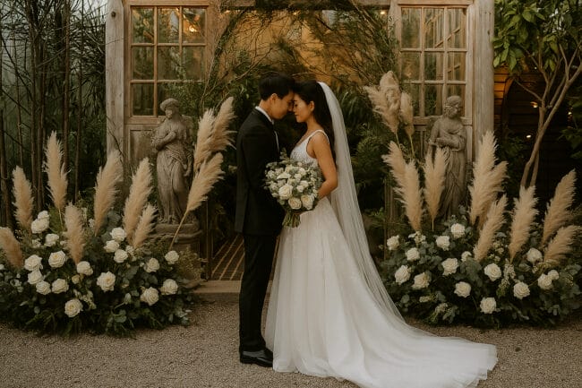 Vietnamese wedding couple in elegant garden ceremony with white roses and pampas grass
