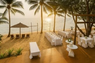 Beach wedding dinner setup at sunset in Vietnam with long white tables, palm trees and ocean view