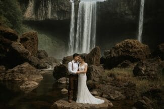 Bride and groom standing in front of waterfalls during an elopement or pre-wedding session in Vietnam’s highlands.