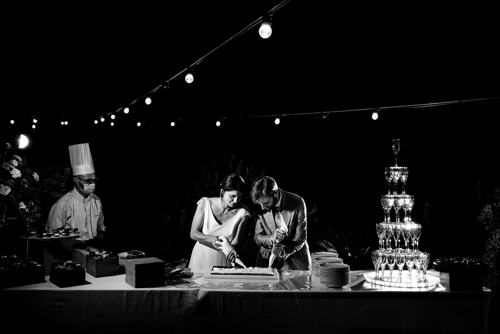 Mariage en noir et blanc : découpe de gâteau sous les guirlandes et tour de champagne