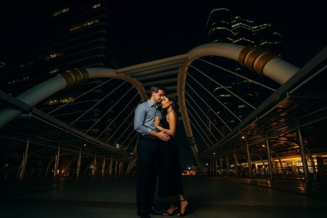 Couple posing at night under the iconic Chong Nonsi Bridge in Bangkok during a pre-wedding photoshoot
