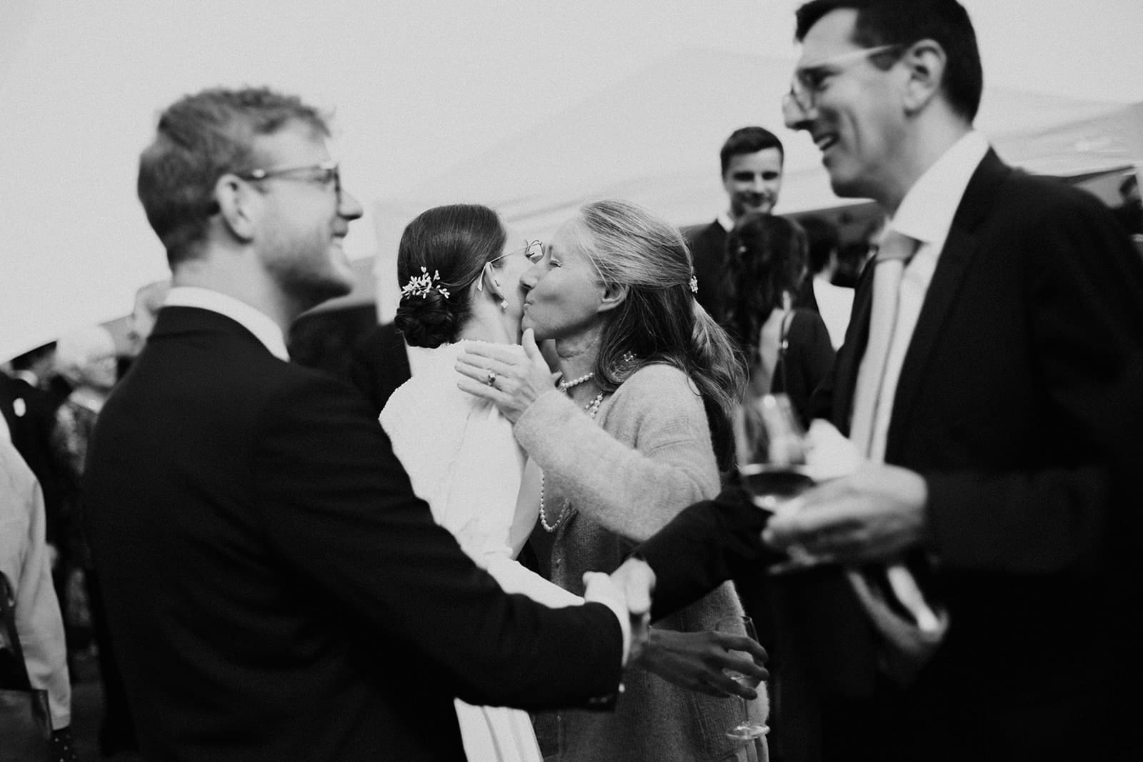 Bride sharing an emotional hug with a guest during the cocktail, warm black and white moment