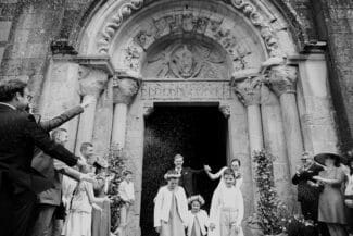 Religious ceremony exit with children and guests throwing rice, black and white photo