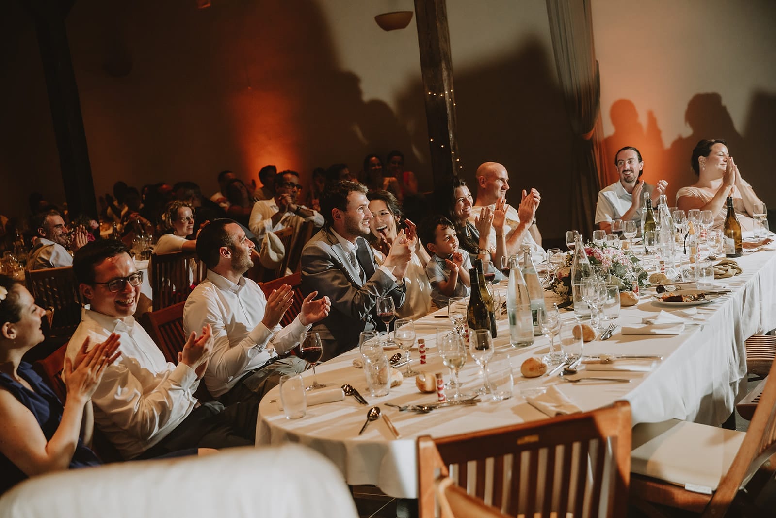Les mariés et leurs invités applaudissent joyeusement un discours pendant le repas de mariage au Château de Pizay
