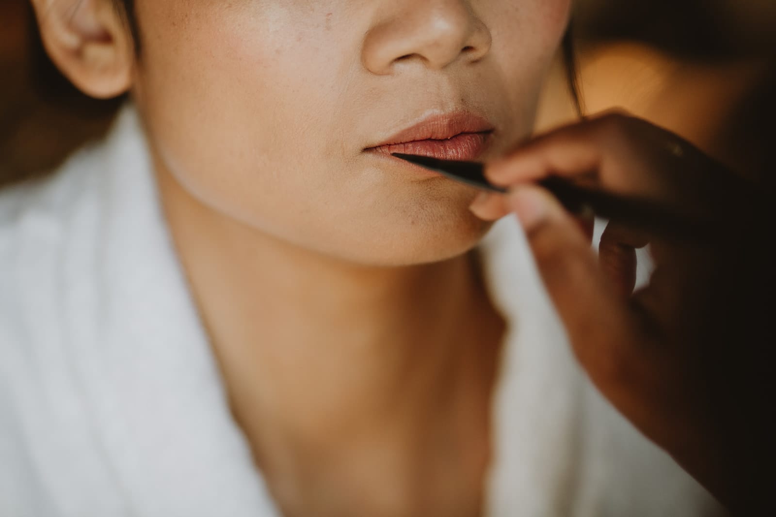Gros plan sur les lèvres de la mariée pendant la mise en beauté, lors de ses préparatifs au Château de Pizay
