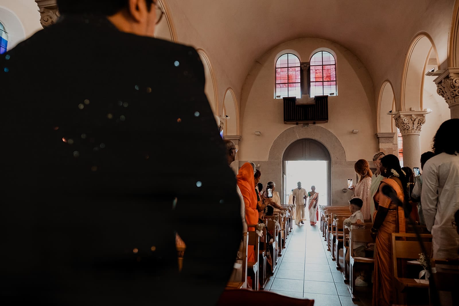 Entrée solennelle de la mariée vêtue d’un sari traditionnel indien, dans une église chrétienne, entourée de proches en tenues colorées