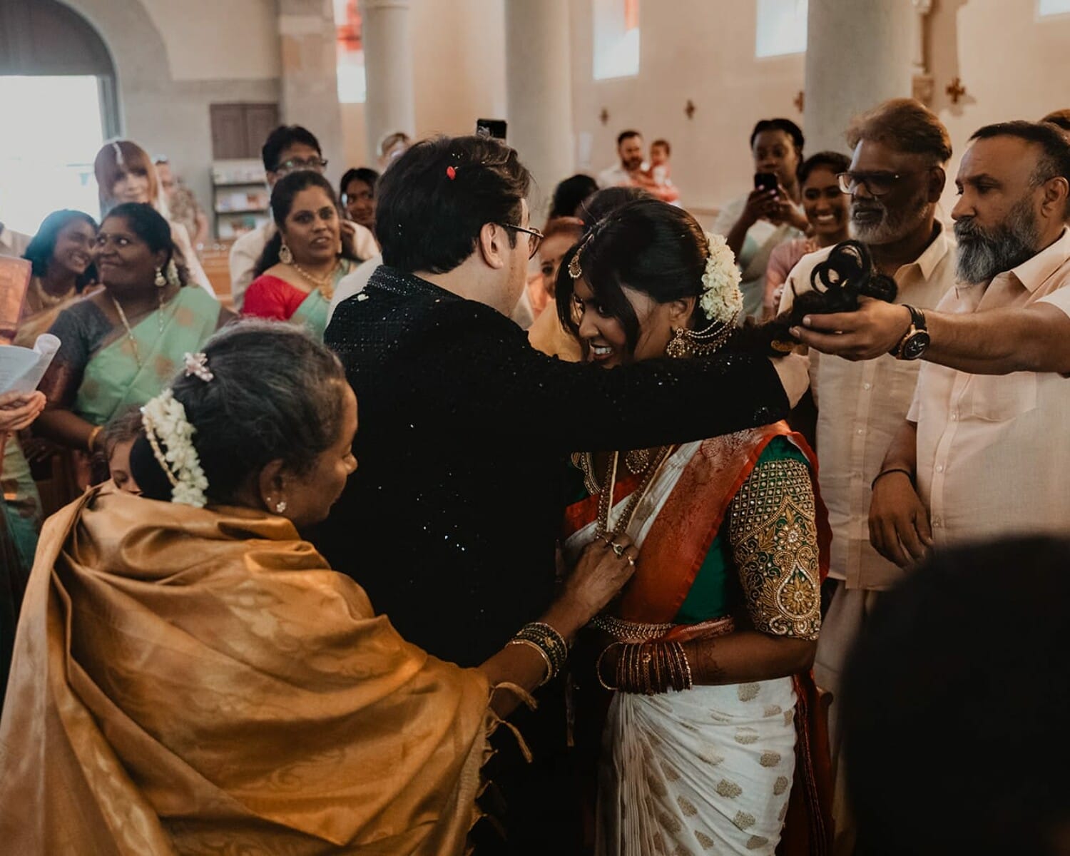 Moment fort du mariage : le marié attache le collier sacré autour du cou de la mariée, entouré par les familles et les chants