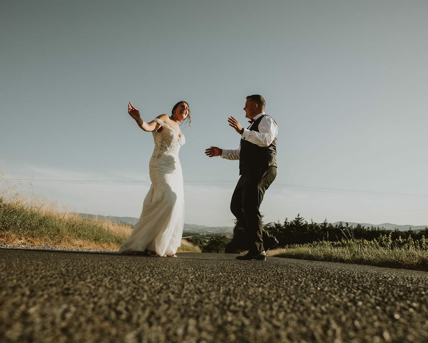 Mariés qui dansent sur une route de campagne dans le Beaujolais, à la lumière dorée du soir