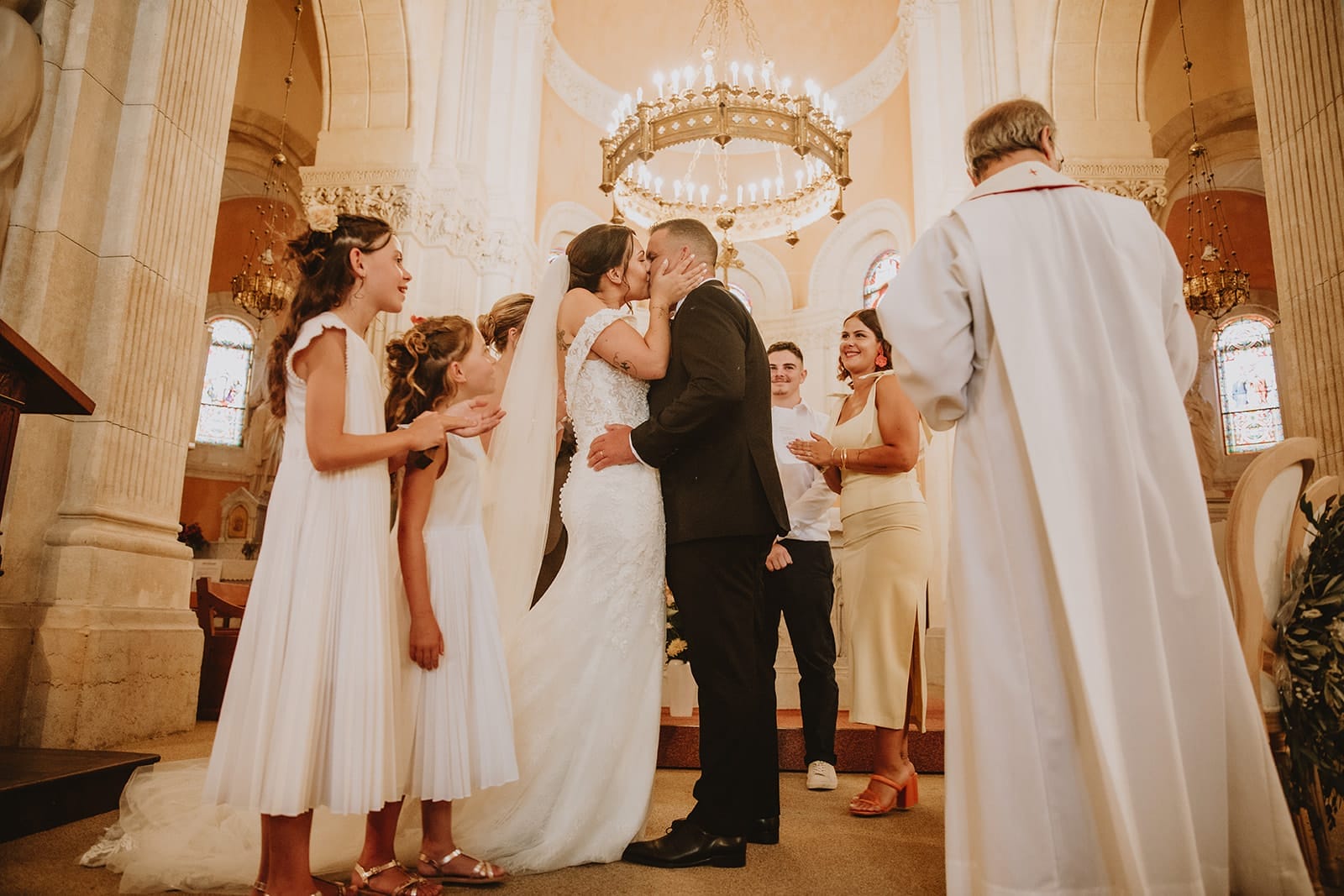 Les mariés s’embrassent dans l’église pendant la cérémonie religieuse dans le Beaujolais, entourés de leurs enfants et invités