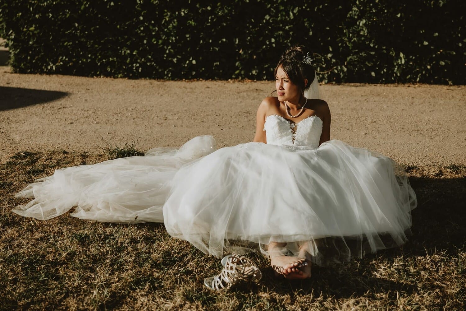 Mariée assise dans sa robe au Château de Beauvoir, chaussures enlevées, lumière dorée