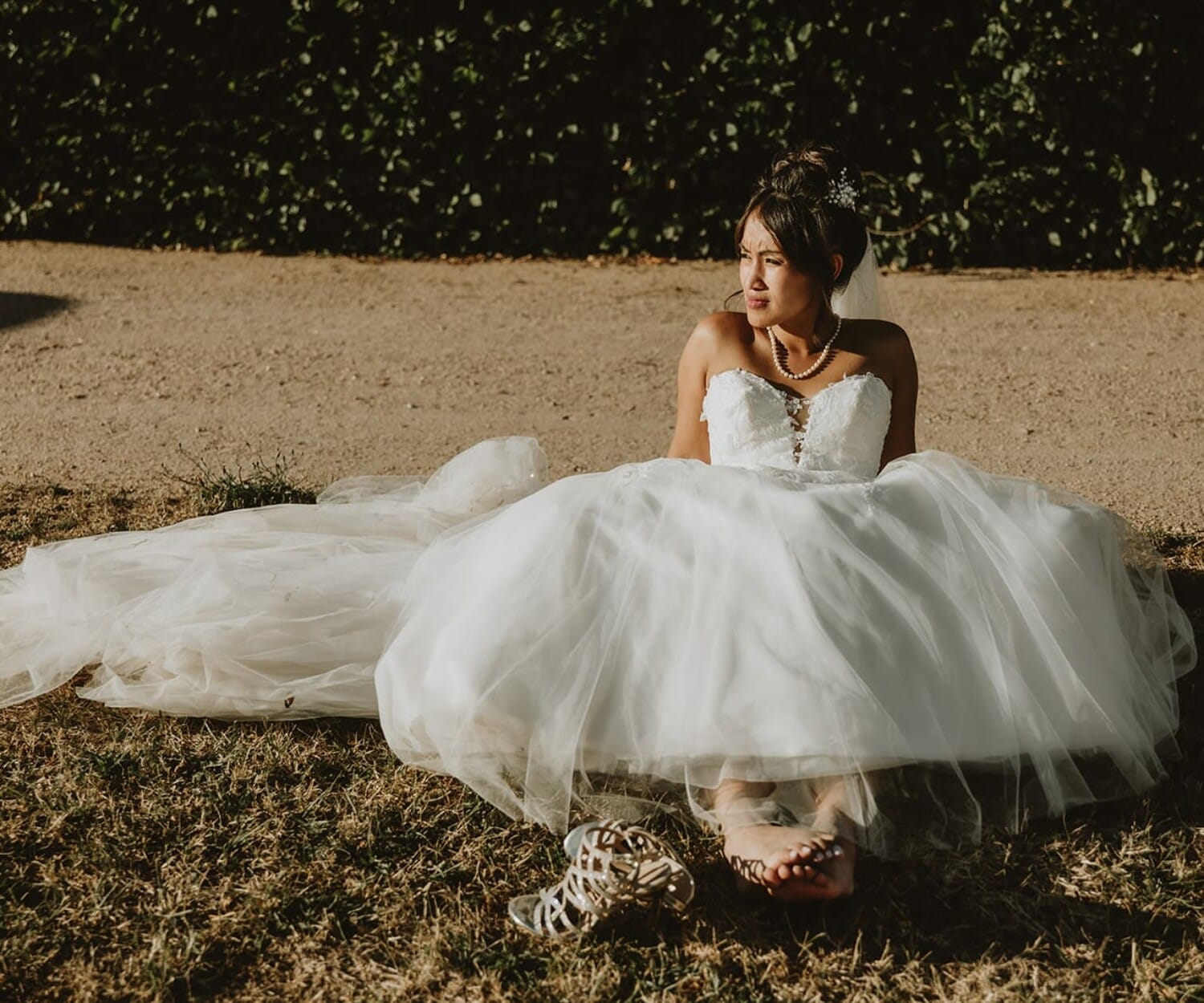Mariée assise dans sa robe au Château de Beauvoir, chaussures enlevées, lumière dorée