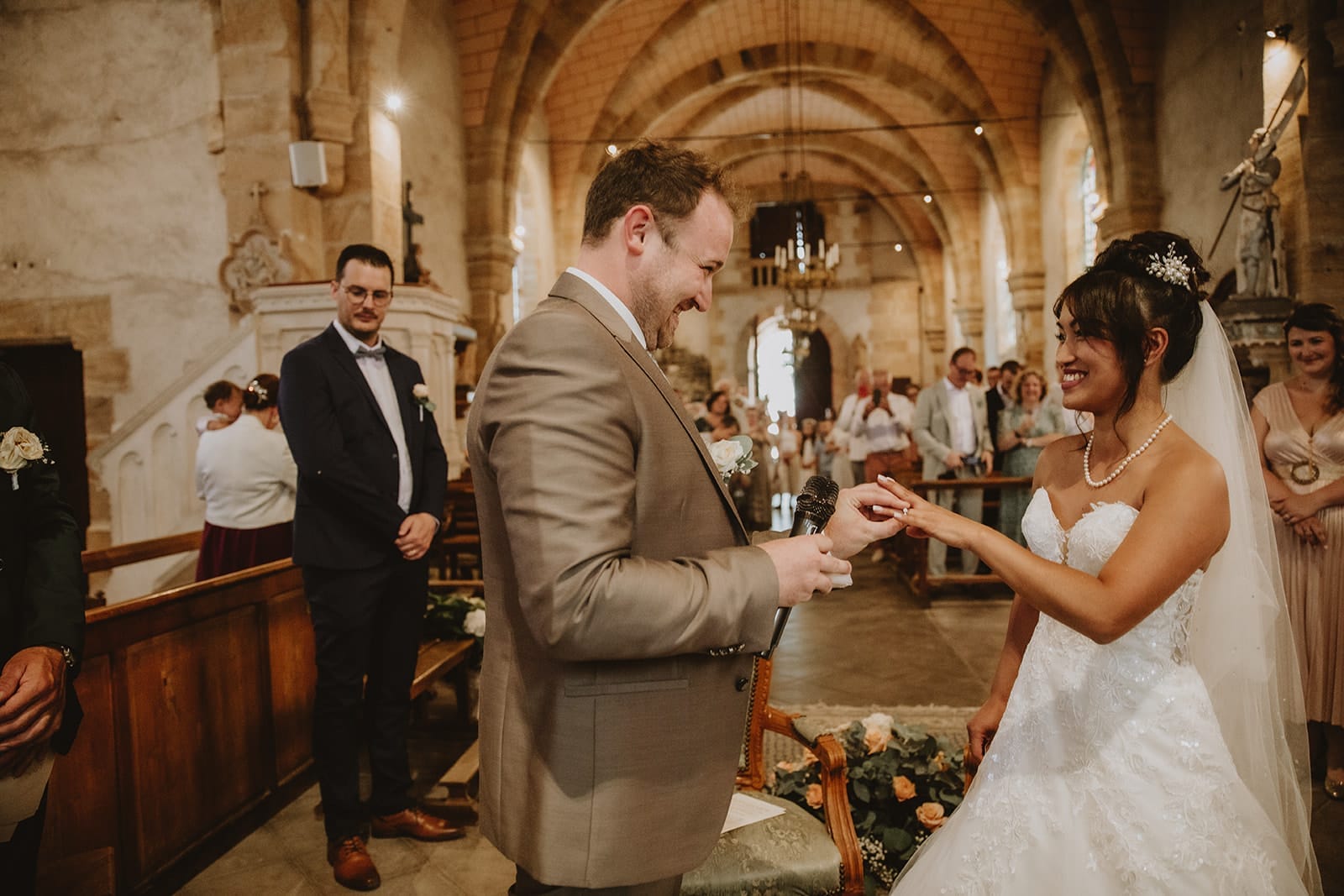 Échange des alliances entre les mariés pendant la bénédiction à l’église de Monetay