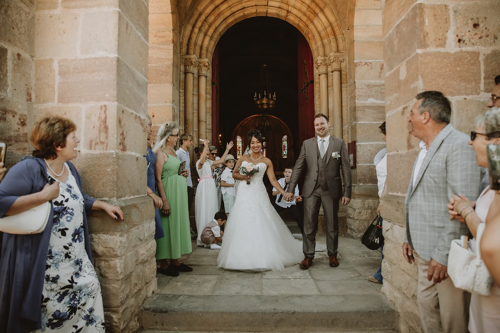 Sortie des mariés main dans la main à l’église de Monetay, entourés de leurs invités